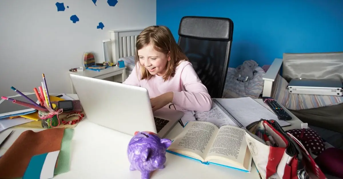 Flicka sitter i skrivbordsstol och tittar på en laptop
