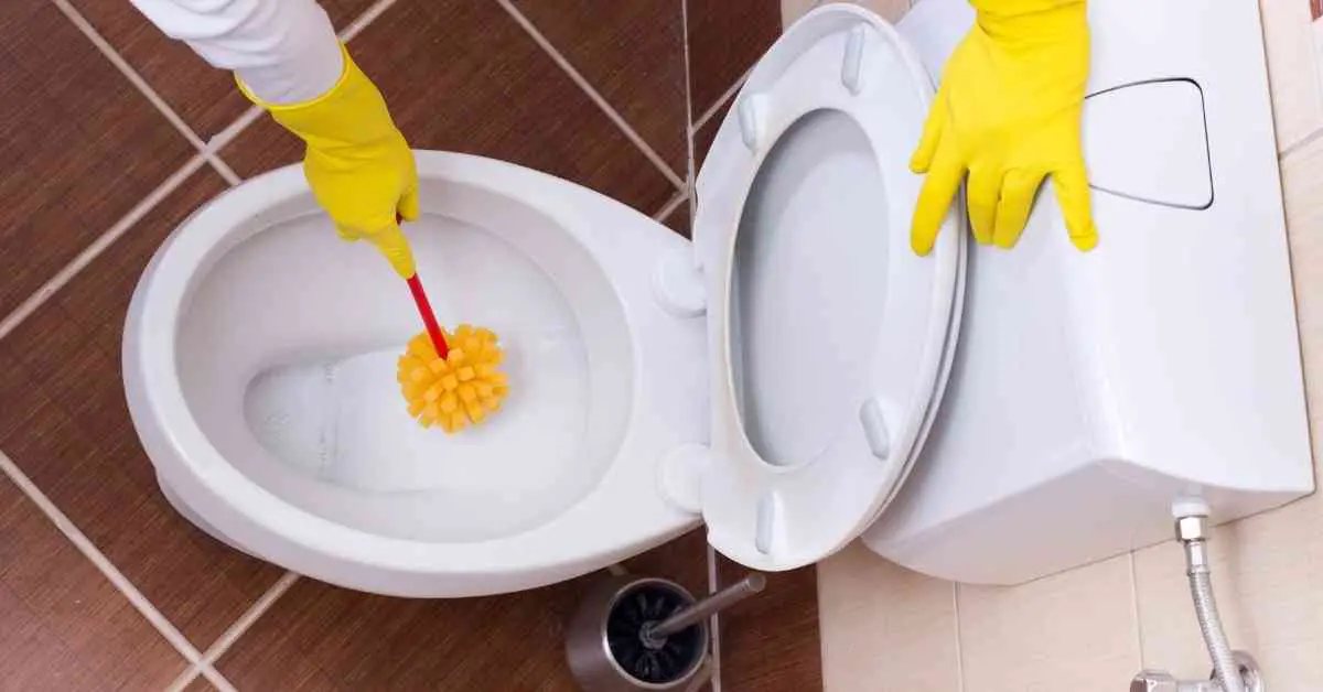 Någon rengör toalett med borste iklädd gula handskar
